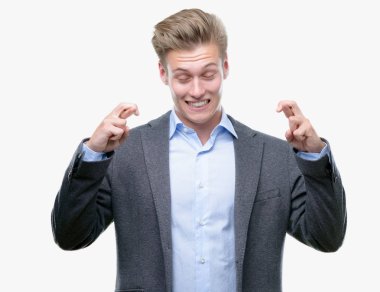 Umut ve gözleri kapalı geçiş parmaklarıyla gülümseyen genç yakışıklı sarışın iş adamı. Şans ve batıl kavramı.