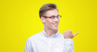 Genç yakışıklı sarışın adam arıyor ve başparmak yanında yukarıyı mutlu yüz ile gülümseyen.