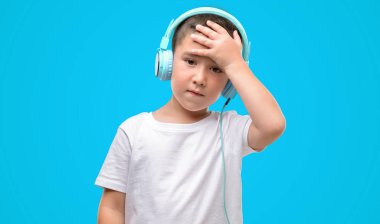 Koyu saçlı küçük çocuk müzik dinleme kafasına, el ile vurguladı kulaklık ile şok utanç ve sürpriz suratla, öfkeli ve sinirli. Korku ve hata için üzgün.