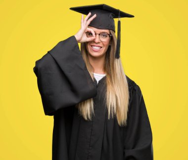 Mutlu yüz el parmaklarının arasından seyir göz üzerinde ok işaretiyle yapıyor gülümseyen ile gözlük ve mezuniyet elbise giyen güzel genç kadın