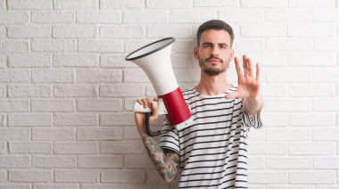 Açık eliyle dur işareti ile ciddi ve kendine güvenen ifade, savunma jest yapıyor megafon tutan genç yetişkin adam