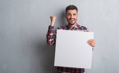 Duygu tezahürat genç yetişkin adam gurur çığlık ve zafer ve başarı çok heyecanlı, kutluyor tuğla duvar holding afiş üzerinde