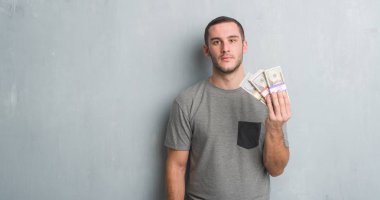 Bir tomar para acımak yüz ciddi düşünüyorum üstünde kendine güvenen bir ifade ile tutarak gri grunge duvarın üzerinden beyaz delikanlı