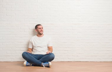 Beyaz tuğla duvar uzak tarafına gülümseme ile yüzünde, doğal ifade bakmaktan katta oturan beyaz delikanlı. Kendine güvenen gülüyor.