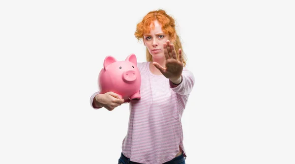 Young Redhead Woman Holding Piggy Bank Open Hand Doing Stop — Stock Photo, Image