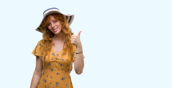 若い赤毛の女性着用夏帽子とドレス の標識をやって大きな笑顔と幸せは優秀な兆候の指で親指 — ストック写真