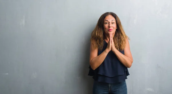 中年拉美裔妇女站在灰色的垃圾墙上祈祷双手一起请求原谅微笑自信 — 图库照片