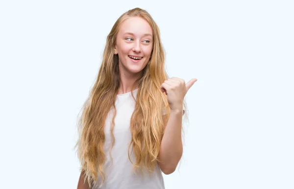 ブロンド十代の若者女性を指すと幸せそうな顔を笑顔で側まで親指で示す — ストック写真