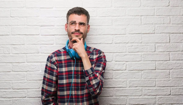 Hombre Adulto Joven Sobre Pared Ladrillo Usando Auriculares Cara Seria — Foto de Stock