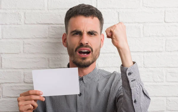 Joven Adulto Sobre Pared Ladrillo Sosteniendo Papel Blanco Molesto Frustrado — Foto de Stock