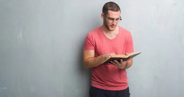 Young Caucasian Man Grey Grunge Wall Reading Book Confident Expression — Stock Photo, Image