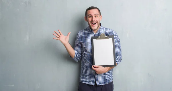 Joven Caucásico Hombre Sobre Gris Grunge Pared Celebración Portapapeles Muy —  Fotos de Stock