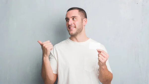 Joven Caucásico Hombre Sobre Gris Grunge Pared Mostrando Blanco Tarjeta — Foto de Stock