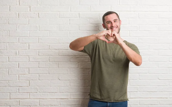 Joven Hombre Caucásico Pie Sobre Pared Ladrillo Blanco Sonriendo Amor — Foto de Stock