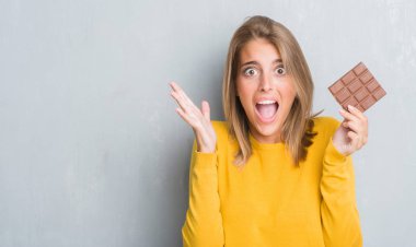 Güzel genç kadın grunge yüzünden çok mutlu ve heyecanlı, çikolata yeme duvar büyük gülümseme ile çığlık ve ellerini kaldırdı kazanan ifade kutluyor zafer gri