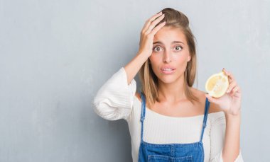 Güzel genç kadın bir limon kafa üzerinde el ile vurguladı tutan grunge gri duvar yüzünden şok utanç ve sürpriz suratla, öfkeli ve sinirli. Korku ve hata için üzgün.