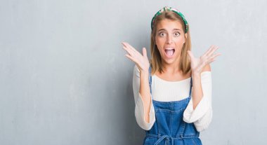 Kocaman bir gülümseme ile çığlık ve ellerini kaldırdı zaferini kutluyor grunge gri duvar çok mutlu ve heyecanlı, kazanan ifade üzerinde duran güzel genç kadın