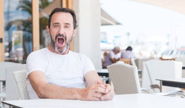 Üst düzey yakışıklı bir sürpriz yüz, korkuyor ve heyecanlı korku ifadesi ile şok korkmuş Teras oturma