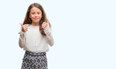 Esmer Latin kız başarı işareti başparmak gülümseyen ve mutlu el ile olumlu hareketi yapıyor. Neşeli bir ifadeyle, kazanan jest kameraya bakıyor.