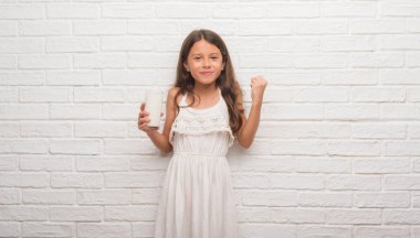 Duygu tezahürat genç İspanyol çocuğun gurur çığlık ve zafer ve başarı çok heyecanlı, kutluyor süt içme Beyaz tuğla duvarın üzerinden