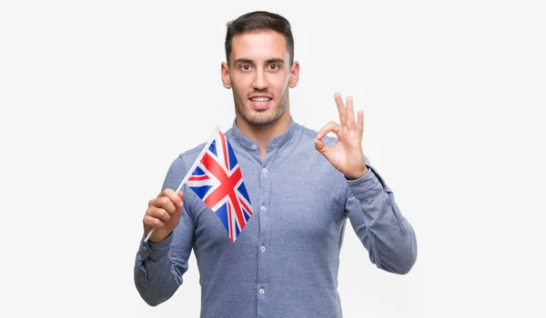 Joven Guapo Sosteniendo Una Bandera Del Reino Unido Haciendo Signo — Foto de Stock