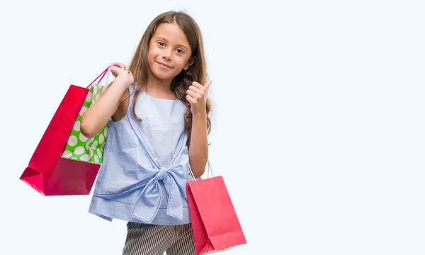 笑顔の サイン 優秀な兆候を親指をやって幸せな買い物袋を保持しているヒスパニックのブルネットの少女 — ストック写真
