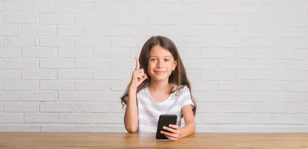 Junges Hispanisches Kind Das Mit Smartphone Auf Dem Tisch Sitzt — Stockfoto