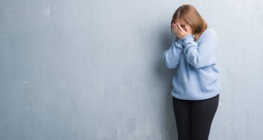 Gri grunge duvar yüz eller ile ağlayarak süre kapsayan üzgün ifade ile gözlüklü Genç Yetişkin kadın. Depresyon kavramı.
