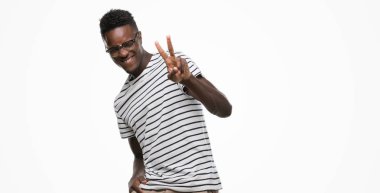 Gözlük ve zafer işareti yapıyor parmak gösterilen kamera seyir gülümseyen lacivert t-shirt giyen genç Afro-Amerikan adam. İki numaralı.