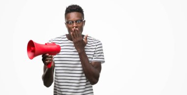 Sessizlik, gizli kavramı megafon kapak ağız hata, korku, ifade için utanç ile şok eliyle tutan genç Afro-Amerikan adam korkuttu