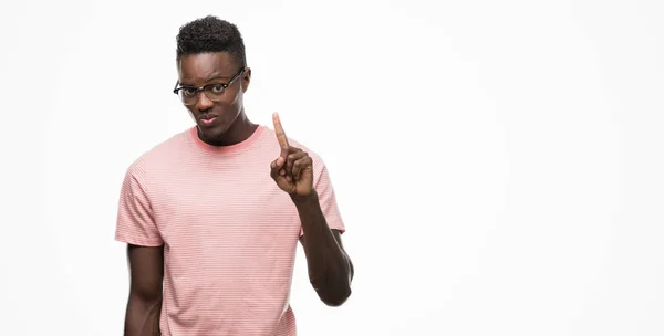 自信を持って 幸せな笑みを浮かべて 指番号のいずれかで上向きの表示とピンクの シャツを着て若いアフリカ系アメリカ人 — ストック写真