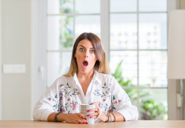 Ev içme kahve bir sürpriz yüz, korkuyor ve heyecanlı korku ifadesi ile şok korkmuş genç kadın