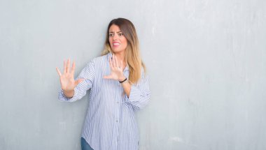 Şokta bağırarak Genç Yetişkin kadın moda iş kıyafeti korkuyor ve korku ifade dur hareketi el ile ile dehşete giymiş gri grunge duvarın üzerinden. Panik kavramı.