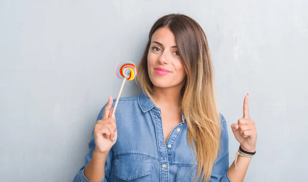 Young Adult Woman Grey Grunge Wall Eating Lollipop Candy Surprised — Stock Photo, Image