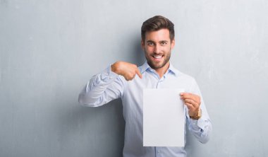 Boş kağıt sayfası sözleşme sürpriz yüz işaret parmağı kendisine tutan gri grunge duvarın üzerinden yakışıklı genç