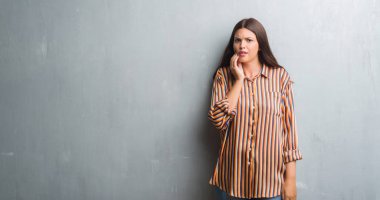 Genç esmer kadın diş ağrısı veya dişlerde dişlerle ilgili hastalık nedeniyle ağız acı ifadesi ile el ile dokunmak grunge gri duvar yüzünden. Diş hekimi kavramı.