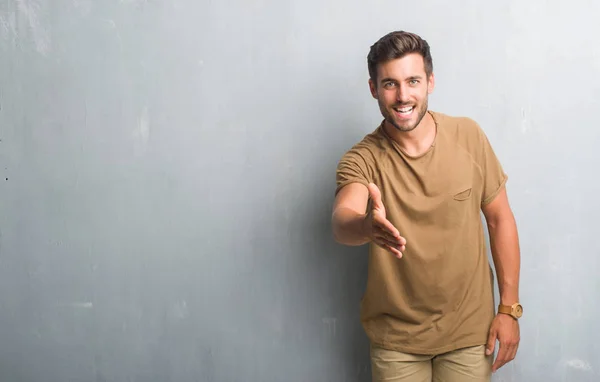 Handsome Young Man Grey Grunge Wall Smiling Friendly Offering Handshake — Stock Photo, Image