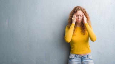 Gri grunge genç Kızıl saçlı kadın duvar baş baş ağrısı için el ile çünkü stres. Migren muzdarip.