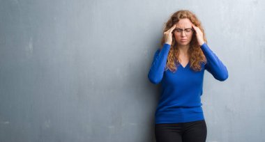 Gri grunge genç Kızıl saçlı kadın duvar baş baş ağrısı için el ile çünkü stres. Migren muzdarip.