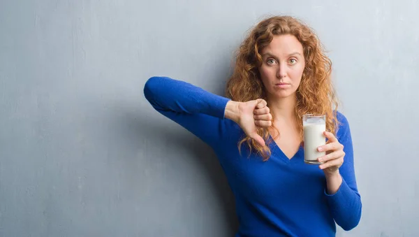 怒った顔 ダウン親指で嫌悪感を示すマイナス記号 拒絶反応の概念とミルクのガラスを飲む若い赤毛の女性 — ストック写真