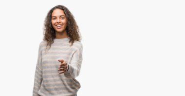 Giyen güzel genç İspanyol kadın kazak gülümseyen dostu sunan el sıkışma tebrik ve davet edici olarak çizgili. Başarılı iş.