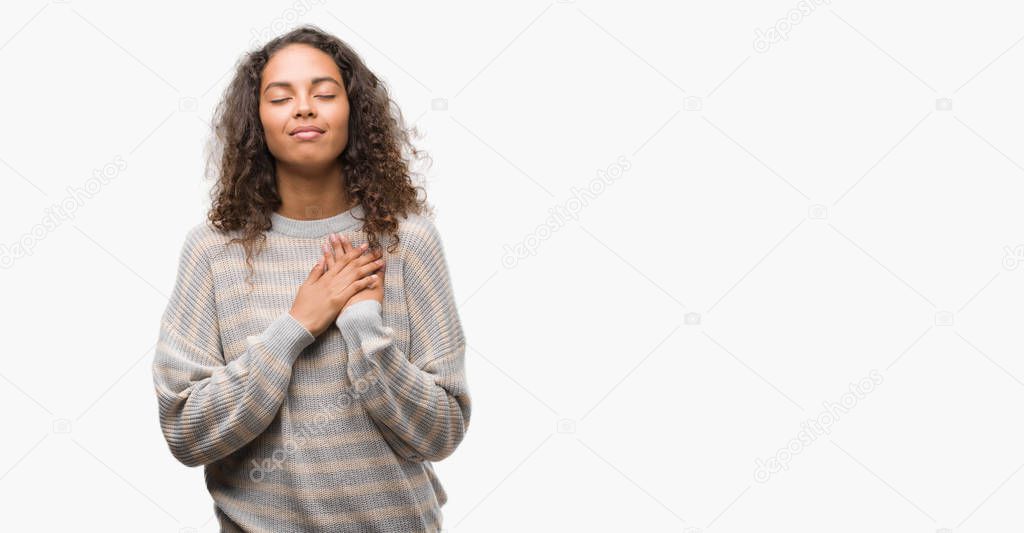 Beautiful young hispanic woman wearing stripes sweater smiling with hands on chest with closed eyes and grateful gesture on face. Health concept.