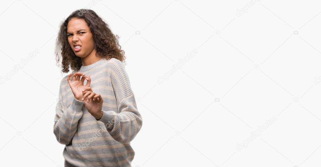 Beautiful young hispanic woman wearing stripes sweater disgusted expression, displeased and fearful doing disgust face because aversion reaction. With hands raised. Annoying concept.