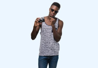 Vintage fotoğraf makinesi ciddi bir yüz düşünme hakkında soru, çok karışık fikir tutan genç Afro-Amerikan adam