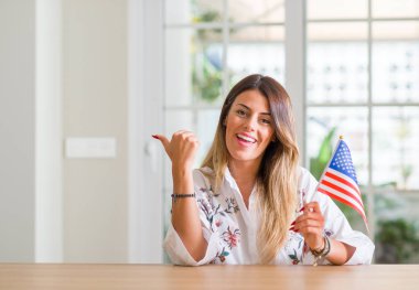 Genç kadın evde, Amerika Birleşik Devletleri el ve parmak ile mutlu yüz gülümseyen ile yukarı dönük bayrak tutan