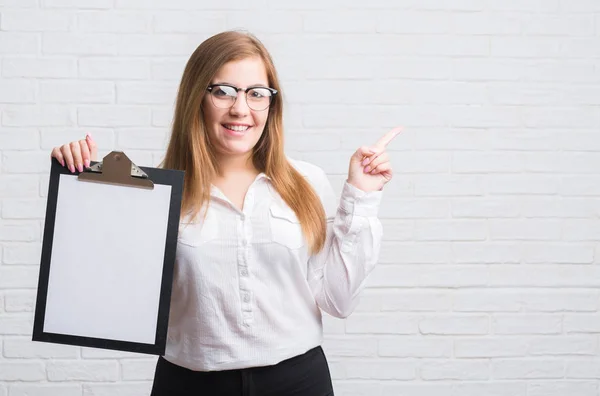 Junge Erwachsene Geschäftsfrau Steht Über Weißer Ziegelwand Und Hält Klemmbrett — Stockfoto