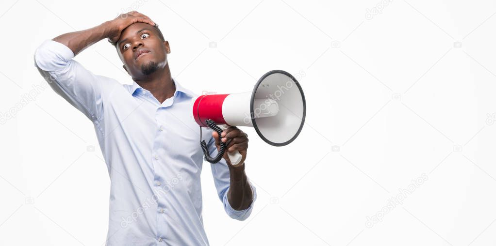 Young african american man holding megaphone stressed with hand on head, shocked with shame and surprise face, angry and frustrated. Fear and upset for mistake.