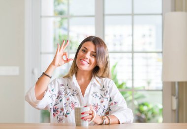 Genç kadın parmakları, mükemmel sembolü olan ok işareti yapıyor kahve ev içme
