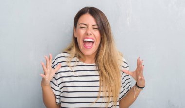 Genç Yetişkin kadın grunge yüzünden kızgın ve silah ile başarı için deli kutluyor t-shirt kaldırdı ve heyecanlı çığlık gözleri kapalı deniz kuvvetleri giyen duvar gri. Kazanan kavramı