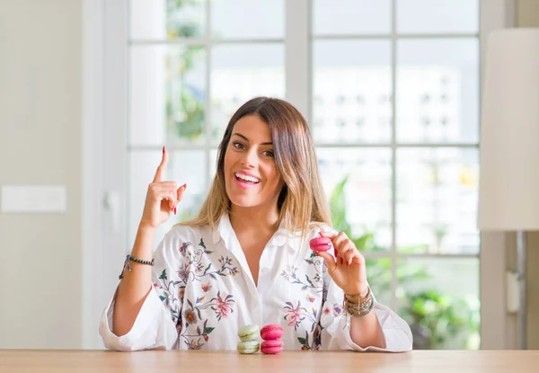 Young Woman Home Eating Macarons Surprised Idea Question Pointing Finger — Stock Photo, Image